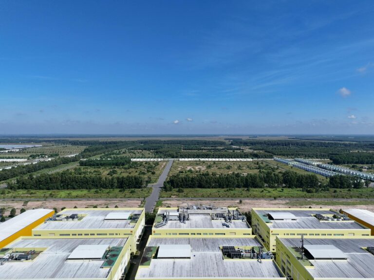Aerial shot of industrial buildings and green landscape in Bình Dương, Vietnam under a clear blue sky.